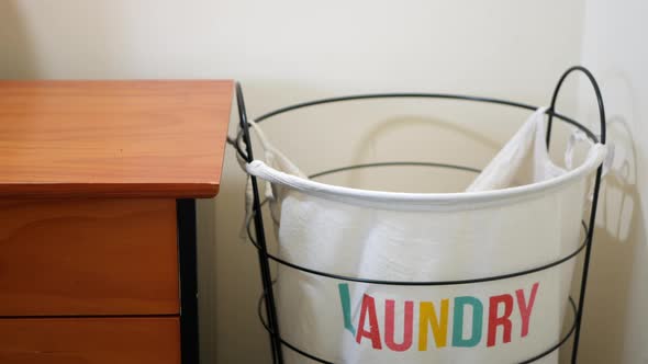 Cloths being tossed into a laundry hamper. Underpants miss and hang off the edge of the basket.