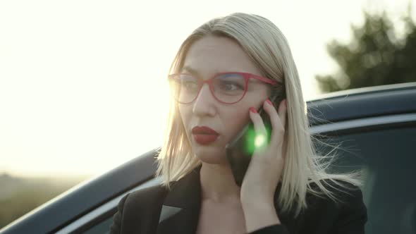 Blonde Talking on the Phone Emotionally at Car on Highway at Sunset