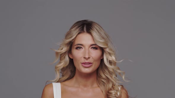 Studio portrait of young and beautiful blond woman over grey background.