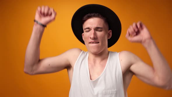 Pleased Young Man in Shirt Dancing Against Yellow Background