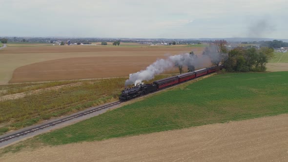 Aerial angled view of a restored steam engine blowing steam and smoke