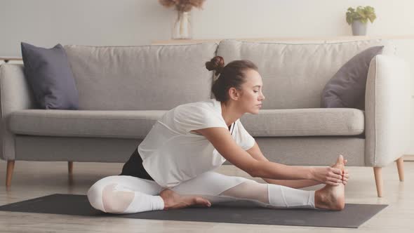 Young Sporty Woman Doing Yoga Stretching Exercises Practicing Pilates on Floor at Home