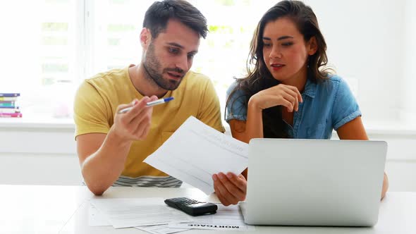 Worried couple calculating their bills with laptop in the kitchen