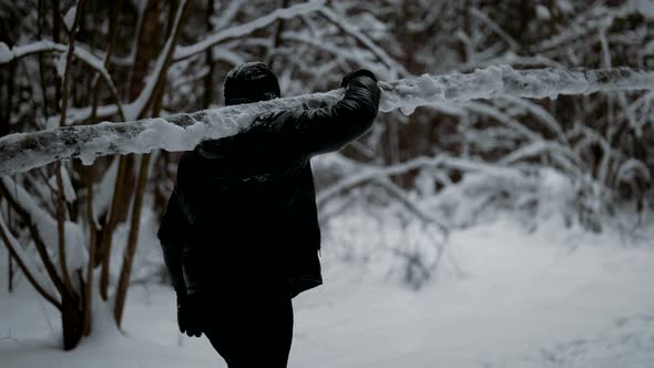 Man is Carrying Log in Forest in Winter Day Training Outdoors or Working in Woodland