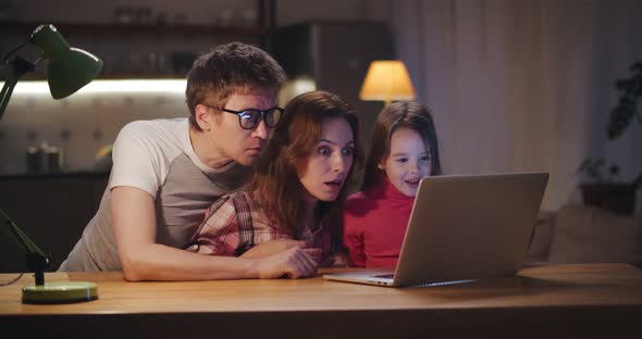 Excited Mom Dad and Daughter Triumph and Win Game on Laptop