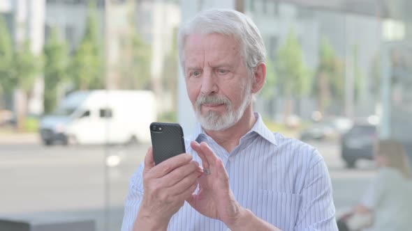 Old Man Celebrating Online Success on Smartphone Outdoor