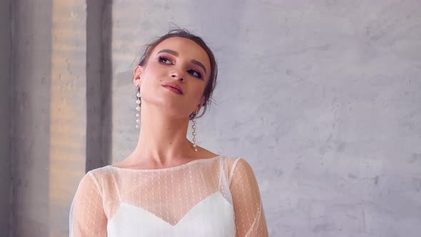 The Girl in a White Dress Poses for the Photographer Turning Her Face