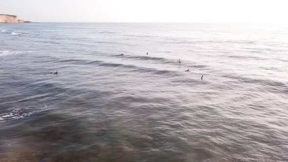 Surfers Surfing At Olon Beach During Golden Hour At Sunset In Summer. - aerial arc shot