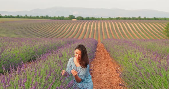 The Beautiful Young Girl Walks Across the Field of a Lavender at Sunset She is Wearing a Long Blue