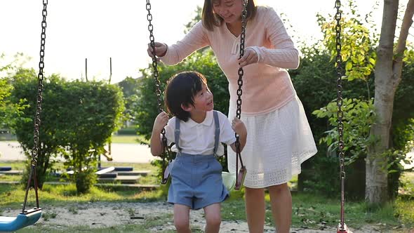 Asian Mother And Son Having Fun On Swing Together In The Park Slow Motion