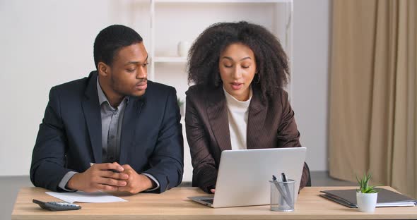 Two People in Office Counting Expenses Using Calculator Afro American Woman Financier Entering