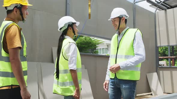 Asian colleague workers wear protective safety helmet and glasses, working onsite of architecture.