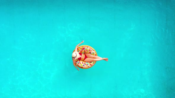 Aerial View of a Woman in Red Bikini Lying on a Donut in the Pool