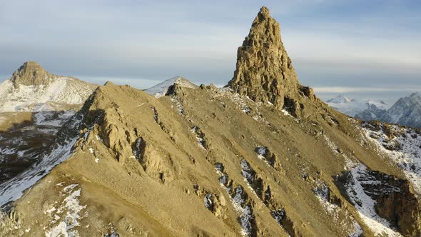 Aerial shot passing close to terrain and climbing above rocky summit "La Maya" revealing alpine land