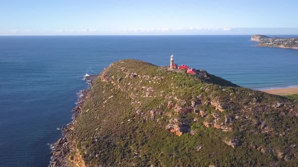 Beautiful Island with a hill top lighthouse with view of two beaches and ocean aerial shot on a clea