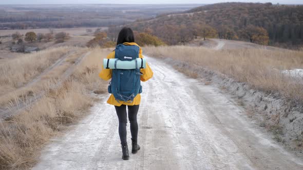 Young Hiker Girl with a Backpack on Top Mountains at Sunset