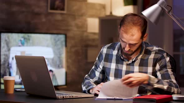 Bearded Businessman Sitting at Desk in Home Office During Night Hours