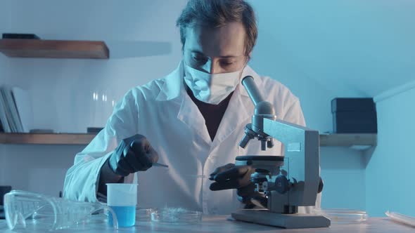 A Male Researcher Puts a Fungus on a Glass Slide Into a Microscope