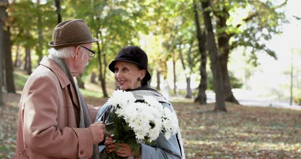 Happy Retired Couple in Love with Bouquet of Flowers Having Fun Talk and Smiling