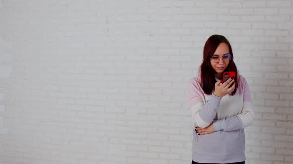 Young Woman Using Smartphone Near Wall