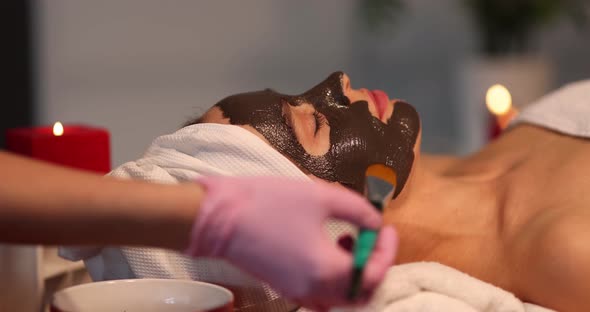 A Beautician Applies a Chocolate Mask to a Woman's Face