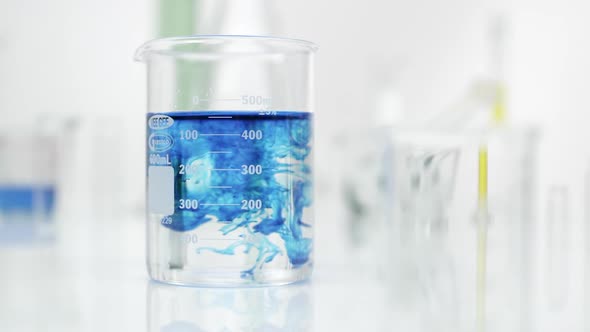 Clear and blue liquid mixing together in beaker