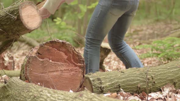 Woman moving logs in forest