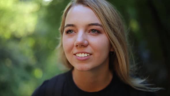 Slow Motion Shot of a beautiful blonde female sitting in the mountains. She is smiling and staring o