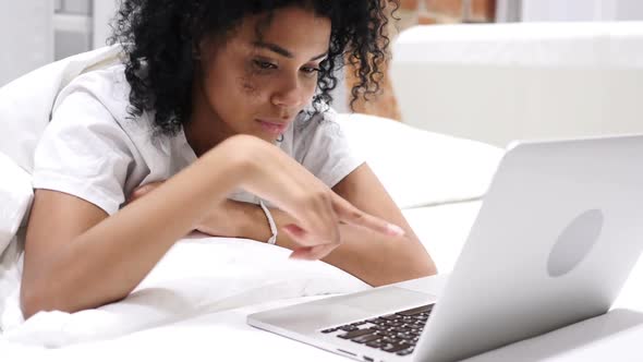 Happy AfroAmerican Woman in Bed Working on Laptop and Reacting to Success