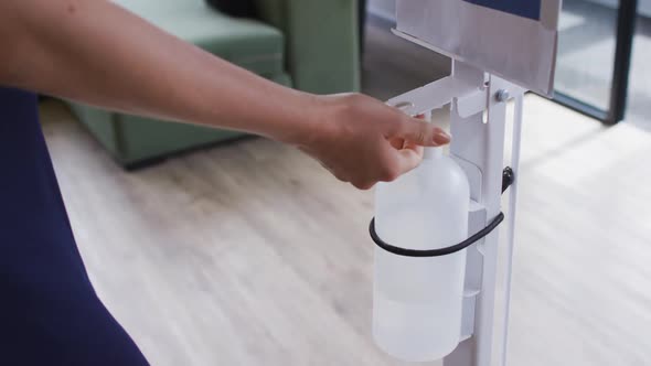 Businesswoman using sanitizer to disinfect hands as he enters the workplace