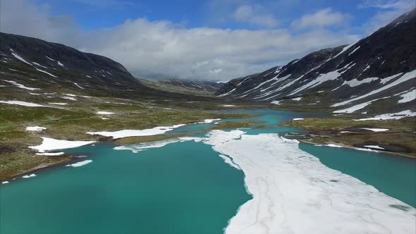 Flying down to the frozen lake in mountain pass in Norway