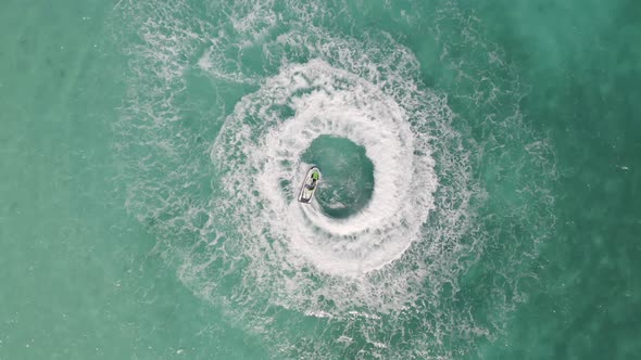 Aerial top view of jet ski or boat drawing a shape on sea ocean turquoise water. Adventure