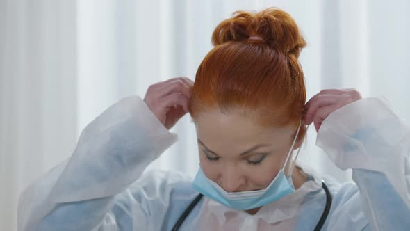 Closeup Portrait of Beautiful Caucasian Redhead Woman with Grey Eyes Putting on Covid Face Mask and