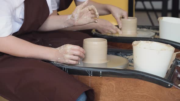 Two Women Make Pottery on a Pottery Wheels, Shaping Clay By Their Hands, Close Up. Pottery Craft