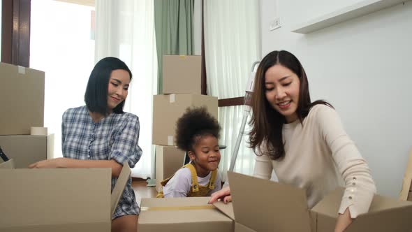 Happy asian women LGBT lesbian couple holding boxes entering new modern house