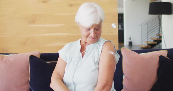 Video of happy caucasian senior woman showing plaster after vaccination