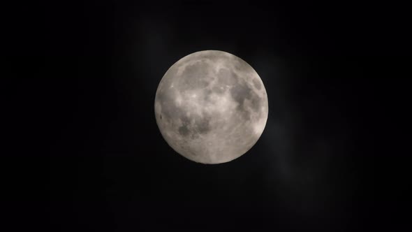 Clouds passing by the full moon, real time shot. Full moon at night with clouds in real time. alt