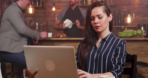 Slide Shot From Right To Left of a Pretty Woman Focused Typing a Text on Her Computer