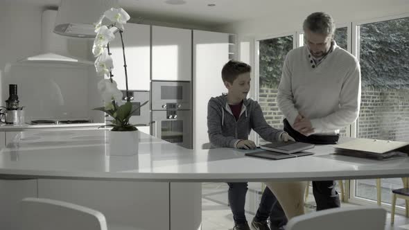 Mature adult male teaching teenage child in kitchen