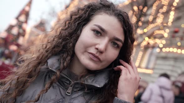 Young Smiling Woman Closeup with Curly Hair Posing on a City Street Wearing a Jacket Cold Season