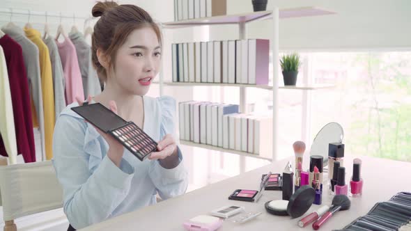 Beauty blogger present beauty cosmetics sitting in front camera for recording video.