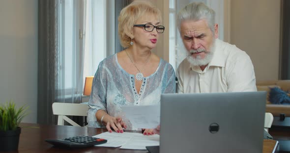 Senior Retired Couple Checking Calculating Bills Paperwork Discuss Unpaid Debt Taxes