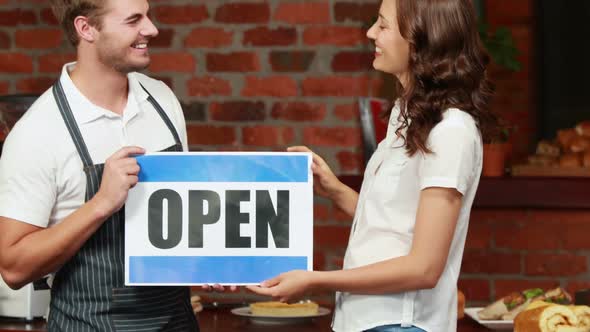 Waiter and Customer Holding a Board with Open Sign