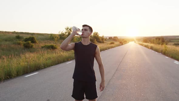 Sportsman Drinking Water From a Bottle and Wiping His Forehead on Country Road