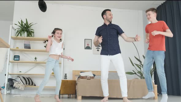 A Young Father of European Appearance Dances with Children at Home in the Living Room