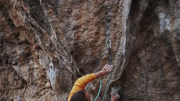 Close Up Top View Handsome Man Rockclimber Climbing on High Rock Cliff Making Hard Move Up Gripping