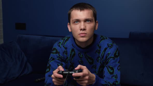 Front View of an Excited Emotional Caucasian Man Playing Video Games and Using Joystick Controller
