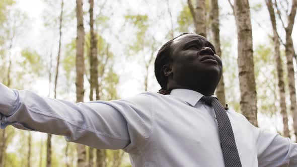 Young African Businessman with Outstretched Hands in the Forest