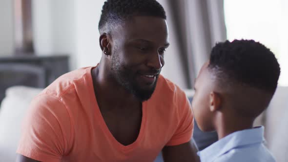 African american father and son embracing on a couch