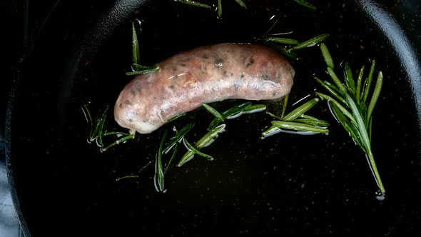 Fatty Bavarian Sausage with Sprig of Rosemary Fried in Frying Pan